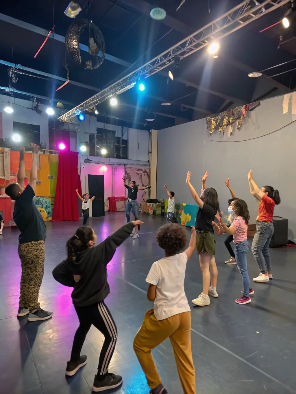 A dynamic image of participants actively engaged in a CAP NANAS theatre workshop, demonstrating acting techniques and collaborative exercises.